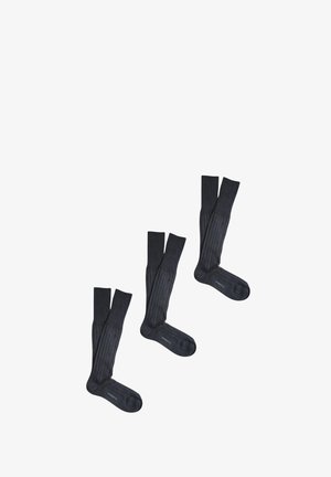 Calze grigio scuro a ginocchio con texture a coste e punta rinforzata. Presentano una finitura liscia e un dettaglio con logo sulla parte inferiore del piede.
