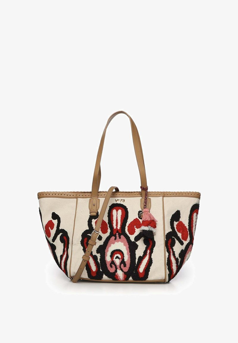 Bolso tote beige con patrones abstractos en rojo, negro y rosa, asas de cuero color canela, correa ajustable para el hombro y borlas decorativas en la parte frontal.