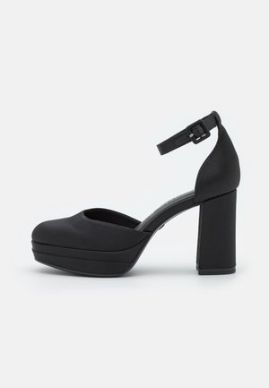 Zwarte platformhakken van satijn met een ronde neus, een enkelbandje en een chunky hak. Soepele textuur en minimalistisch ontwerp.