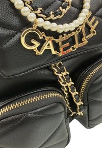 Borsa a tracolla in pelle nera con texture trapuntata, dettagli dorati e tracolla a catena. Mostra il nome "GAEL" in lettere dorate con dettagli rossi.