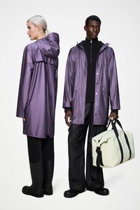 Μωβ αδιάβροχο παλτό με κουκούλα, εμπρός κλείσιμο με πιέτες, συνδυασμένο με μαύρο παντελόνι και μπότες· κρατώντας μια ανοιχτοπράσινη τσάντα duffel με μαύρα λουριά.