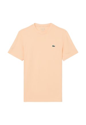 Camiseta de manga corta color melocotón claro con cuello redondo y pequeño logo verde de cocodrilo en el pecho izquierdo.