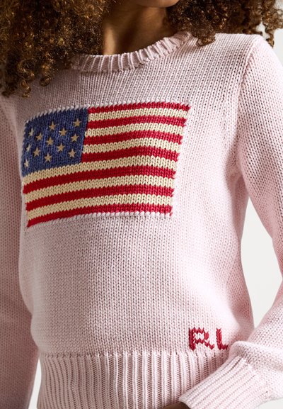 Rosa strikket genser med et stort amerikansk flaggdesign på forsiden, med røde og blå striper, og ribbestrikkede mansjetter og kant.