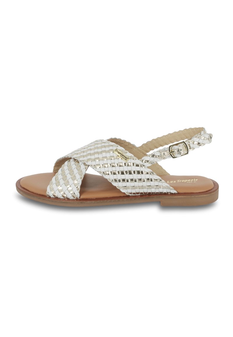 Silver woven flat sandals with crossover straps, beige synthetic insole, adjustable ankle strap, and a smooth brown outsole.