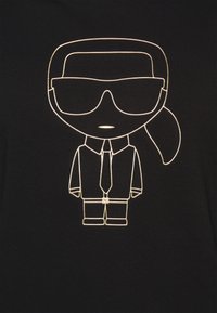 Tela negra con una ilustración en contorno dorado de una figura con gafas de sol, un traje y una corbata, detallada con una coleta y acentos de botones.