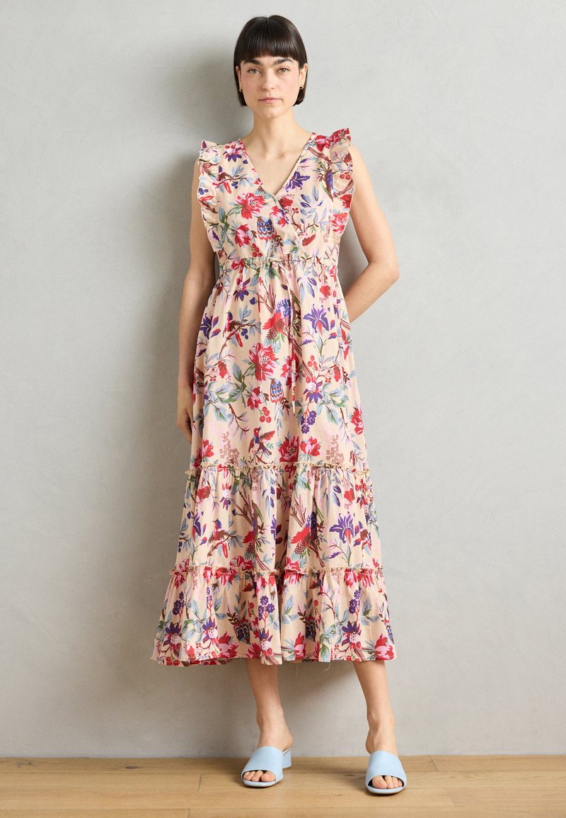 Rochie maxi florală cu mâneci volănaș, dintr-un material roz cu flori multicolore. Design în straturi, cu o fustă fluidă. Sandale bleu deschis.