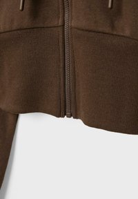 Bruine zip-up hoodie met textured stof en ribbenaccenten, met een centrale rits en een schone, minimalistische uitstraling.