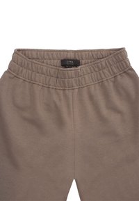 Brązowe dresy z rozciągliwego materiału z elastycznym pasem i metką z napisem "OPRA". Gładka tekstura, średni stan, odpowiednie do codziennego noszenia.