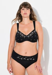 Musta alusvaatesetti, joka sisältää paisley-kuvioilla varustetut rintaliivit, säädettävät hihnat ja yhdisteet korkean vyötärön alusvaatteet, joissa on pitsiyksityiskohtia.