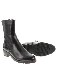 Botas de cuero negras hasta el tobillo con puntera redonda, costuras mínimas, un tacón de madera contrastante y suelas de goma con un patrón de agarre texturizado.