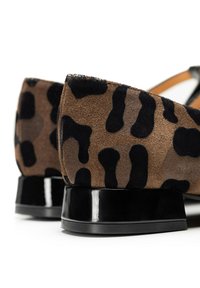 Scarpe in suede con stampa leopardata e tacchi a blocco neri e lucidi. Il motivo presenta tonalità di marrone e nero, evidenziando una superficie texture.