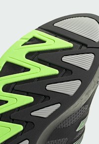 Čierna atletická podrážka so zelenými textúrovanými akcentmi a šedými ryhovanými časťami, navrhnutá pre trakciu a odolnosť.