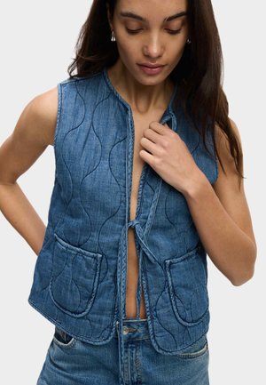 Gilet en denim avec un motif matelassé, doté d'une fermeture à nouer à l'avant et de deux poches à rabat. Le tissu est bleu avec une finition texturée.