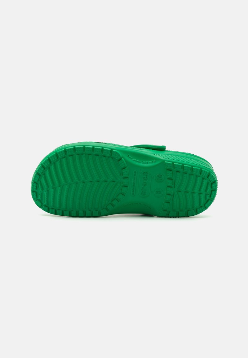 Suela de zapato de goma verde con un patrón texturizado para el agarre, con acentos circulares y detalles del modelo grabados en el lado.