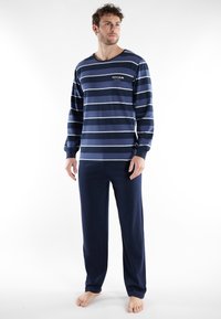 Ensemble de pyjama bleu marine avec manches longues et pantalon, arborant des rayures blanches horizontales et un petit logo sur la poitrine. Tissu au toucher doux.