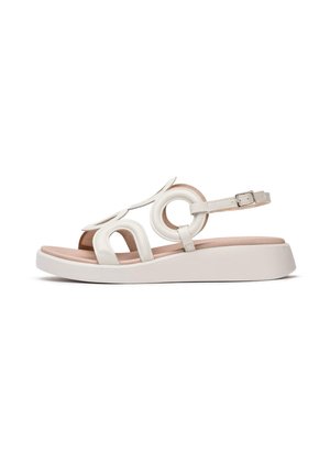 Hvid sandal med cirkulære udsparinger, justerbar ankelrem og en kontrasterende blød beige indersål. Udstyret med en platformsål for ekstra højde.