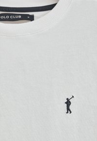 Biała bluza z miękkiego materiału, z małą granatową wyszywaną postacią trzymającą kij golfowy na przodzie. Klasyczny okrągły dekolt.