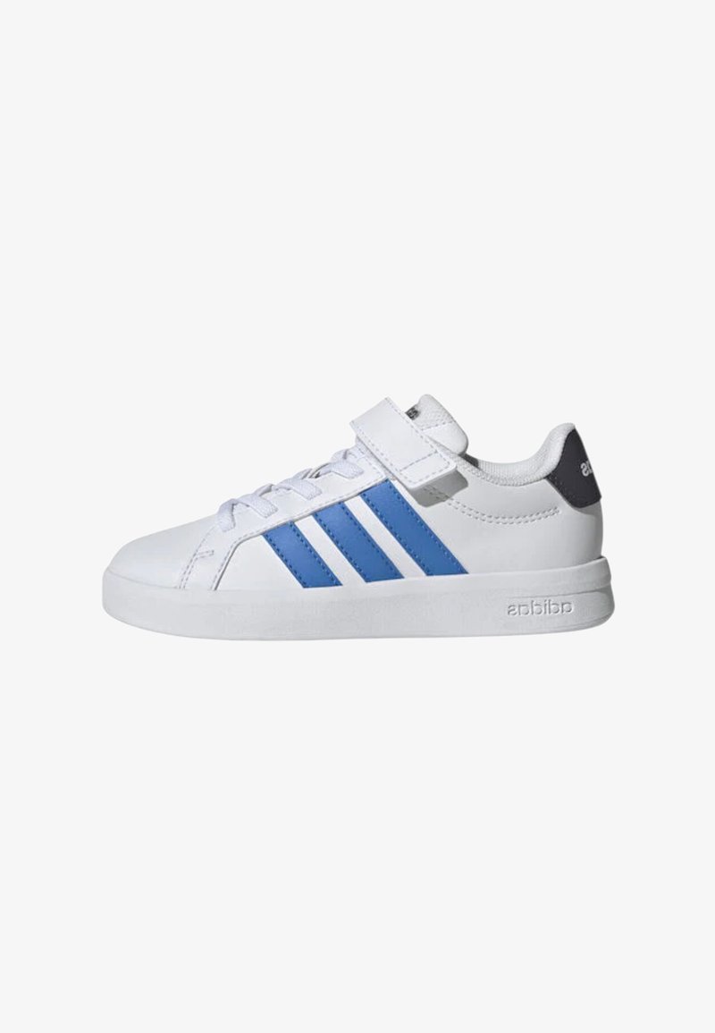 Zapatilla blanca con rayas azules, cierre de cordones y tira de Velcro, talón con etiqueta de marca y suela plana.