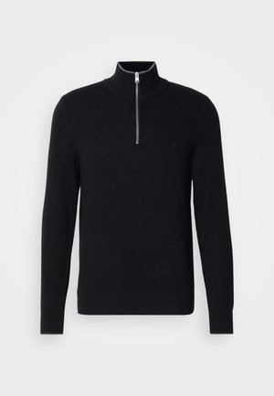 Schwarzer Pullover mit hohem Kragen und Reißverschluss. Besitzt eine glatte Textur und eine figurbetonte Silhouette, mit dezentem Logo-Detail auf der Brust.