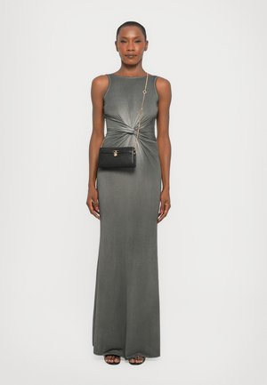 Robe maxi en jersey gris avec un détail à l'avant tordu. Associée à un sac bandoulière noir avec un fermoir en ton doré.