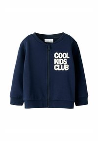 Tumed sinise värviga lastele mõeldud tõmblukuga sviiter, millel on pehme tekstuur ja kreemivärvi tekst "COOL KIDS CLUB". Ribitud varrukad ja helk. 