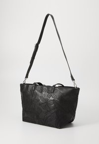 Bolso tote de cuero negro con patrones de hojas en relieve, asas dobles en la parte superior y una correa de hombro ajustable. Forma estructurada y textura suave.