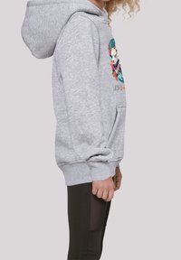Sudadera con capucha gris con un bolsillo frontal y un diseño gráfico colorido. Presenta puños y dobladillo acanalados, combinada con leggins negros.