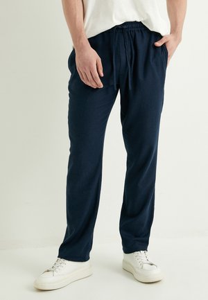 Pantalones jogger de corte relajado en azul marino, confeccionados con una tela suave, con cintura elástica y cordón, bolsillos laterales y diseño de pernera ajustada.