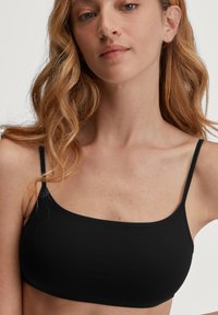 Zwarte bralette met dunne bandjes, gladde textuur, rechthoekige vorm, naadloze constructie en een eenvoudig, minimalistisch ontwerp.