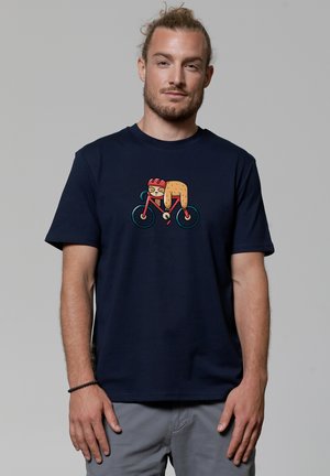 Navy blauwe katoenen shirt met een kleurrafico van een cartoonfiguur op een fiets, met opvallende details zoals een rode helm en duidelijke vormen.
