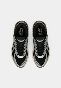 Sorte og sølv sneakers med mesh-stof, snørebånd-design og en fremtredende logo på tungen. Har glatte accenter og en teksturert såle.