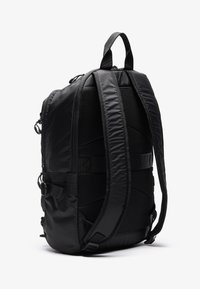 Sac à dos noir avec tissu texturé et accents lisses. Comprend des bretelles en mesh rembourrées, une poignée supérieure et des boucles latérales réglables pour plus de fonctionnalité.