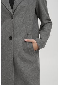 Cappotto grigio in lana con colletto a rever, due tasche frontali e chiusura con un bottone nero. Tessuto morbido con una vestibilità su misura.