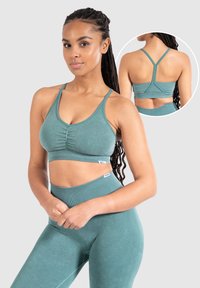 Top deportivo color aguamarina con fruncidos, tirantes anchos y un diseño sin costuras. Combinado con leggings de tiro alto en aguamarina que presentan acentos texturizados.