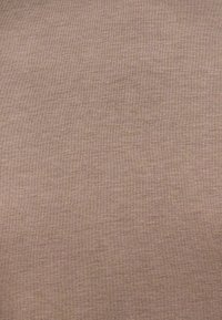 Svijetlosmeđi pleteni materijal s glatkom teksturom i suptilnim varijacijama u nijansi, stvarajući mekanu i ravnomjernu površinu. Nema vidljivih uzoraka ili dizajna.