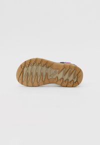 Sandal sole with a rubber base, featuring a zigzag tread pattern for grip. The bottom displays a logo and has a mix of light and dark brown colors.