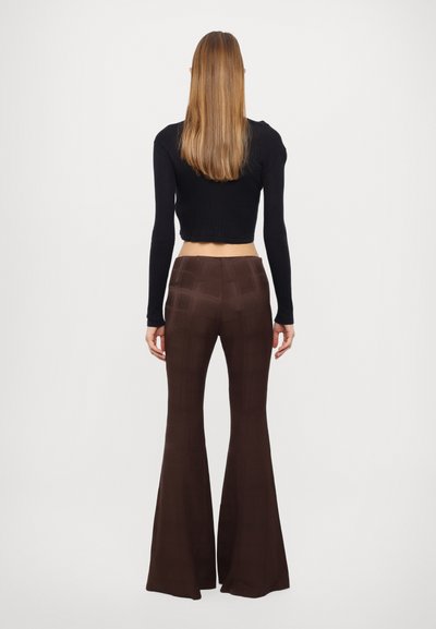 Black cropped ribbed long-sleeve top paired with brown plaid flared pants, shown from the back. Smooth fabric texture and fitted design.