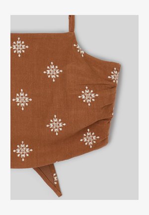 Masque facial en tissu marron avec motifs géométriques d’étoiles blanches et boucles d’oreilles ajustables sur fond gris.