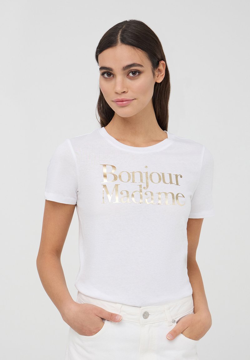 T-shirt bianca a maniche corte con stampa metallica dorata "Bonjour Madame" sul davanti. Tessuto morbido con un classico scollo rotondo.