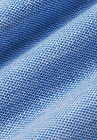 Teksturowana tkanina w jasnoniebieskim i białym kolorze, z plecionym wzorem, widocznymi liniami stębnowania oraz miękką, gładką powierzchnią.