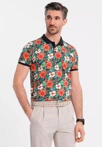 Kortärmad polotröja i grön tyg, med ett livligt blommönster med röda och vita blommor, svart krage och slim fit-design.