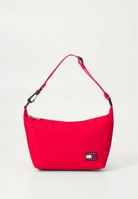 Bolso de hombro rojo de Tommy Jeans con correa ajustable y parche de logo negro, cierre superior con cremallera, sobre un fondo claro y sencillo.