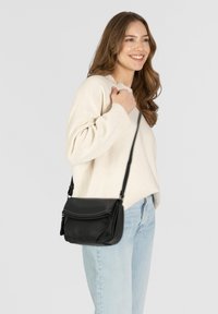 Borsa a tracolla nera in pelle testurizzata, con tasca frontale con zip, tracolla regolabile e forma elegante e compatta.