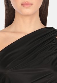 Abito nero con design a spalla singola e dettagli arricciati, realizzato in tessuto morbido e leggero.