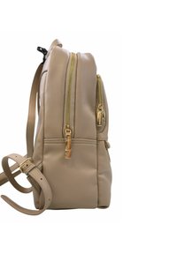 Zaino in pelle beige con zip dorate, due tasche frontali, tracolla regolabile e texture liscia, che mette in mostra un design compatto e linee pulite.
