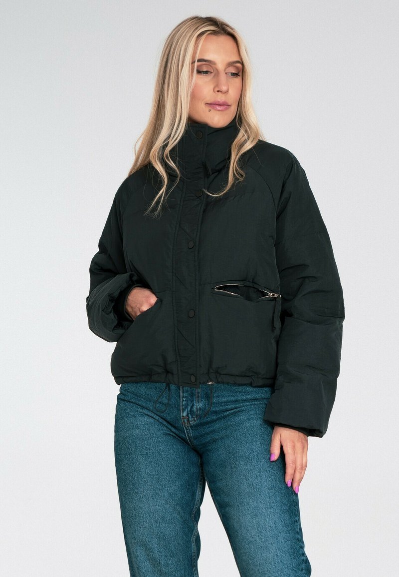 Czarna kurtka puchowa z wysokim kołnierzem, zapięciem na napy i zasuwaną kieszenią. Materiał wydaje się gładki, z lekko błyszczącym wykończeniem.