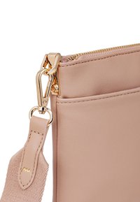 Rosa Lederhandtasche mit glatter Textur, ausgestattet mit einem goldenen Reißverschluss und einem abnehmbaren Riemen mit einem goldenen Hardware-Verschluss.