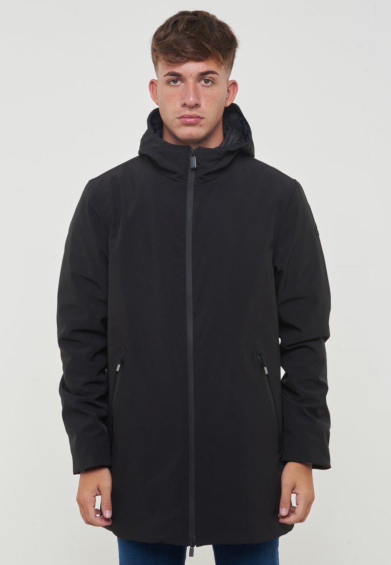 Giacca nera impermeabile con cappuccio, slim fit, dotata di zip frontale, due tasche laterali con zip e tessuto texture.