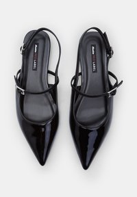 Escarpins slingback en cuir verni noir avec un bout pointu, bride de cheville ajustable et semelle intérieure rembourrée. Marque visible à l'intérieur.