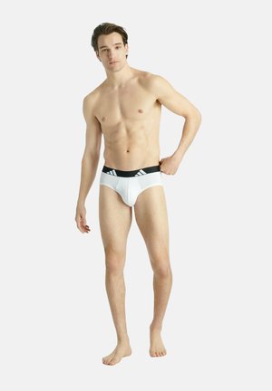 Vita kalsonger med en svart elastisk midja som har tre vita ränder. Tillverkade av mjukt material som ger en åtsittande passform.